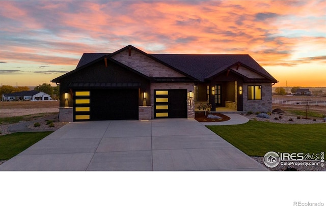 view of front of house featuring an attached garage, driveway, a yard, and stone siding