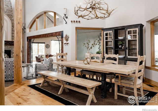 dining area with a towering ceiling, a chandelier, and hardwood / wood-style flooring