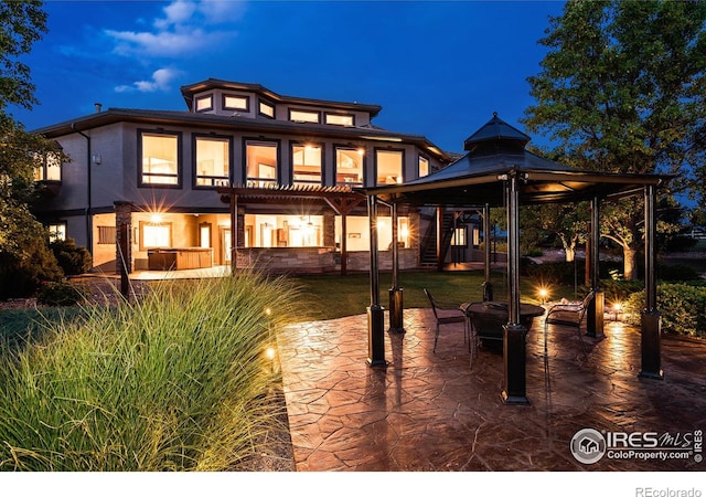 back house at twilight featuring a patio and a pergola