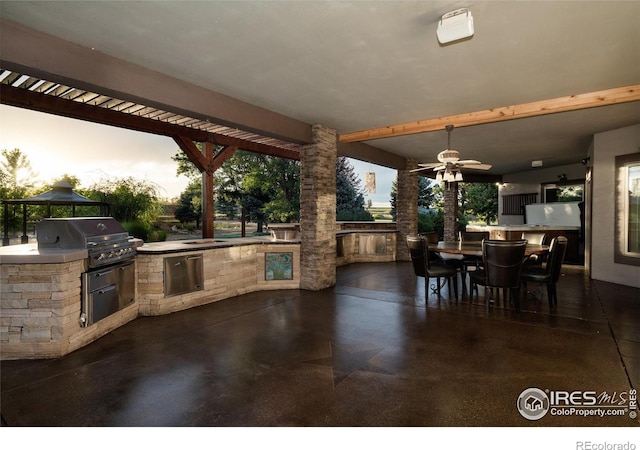 patio terrace at dusk with area for grilling, ceiling fan, and grilling area