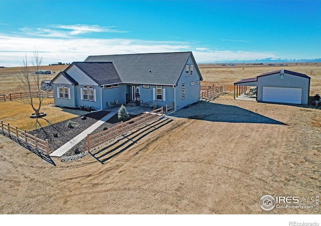 view of front of house featuring a rural view, a garage, and an outdoor structure