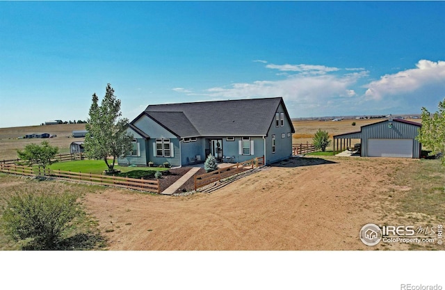 view of front of home featuring an outdoor structure, a garage, and a rural view