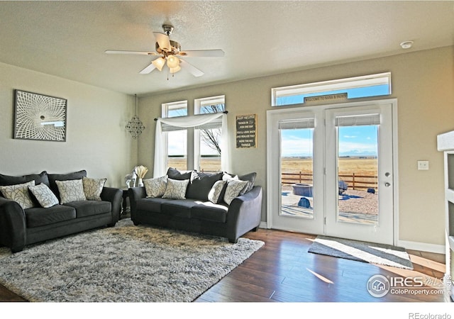 living room with a textured ceiling, dark hardwood / wood-style flooring, and ceiling fan