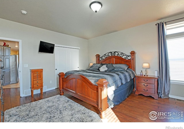 bedroom featuring a closet, dark hardwood / wood-style floors, and stainless steel fridge