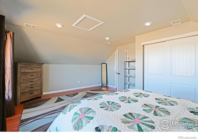 bedroom with vaulted ceiling, dark hardwood / wood-style flooring, and a closet