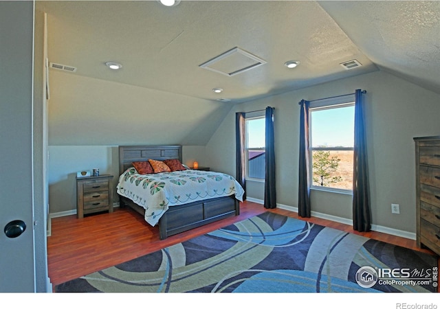 bedroom featuring hardwood / wood-style flooring, lofted ceiling, and a textured ceiling