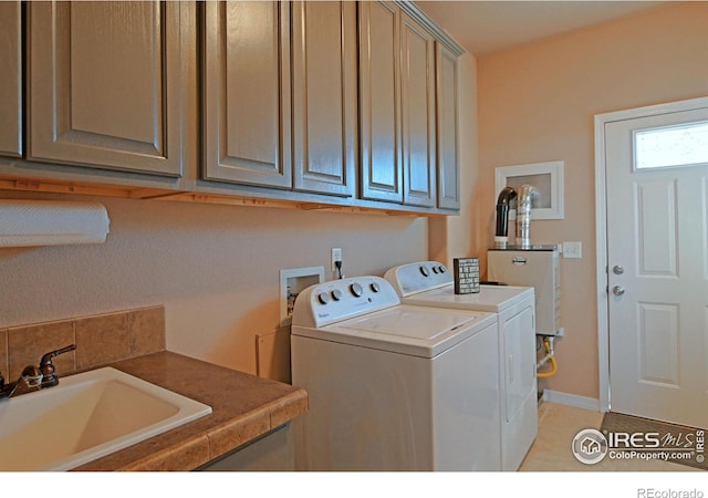 laundry room featuring cabinets, gas water heater, washer and dryer, and sink