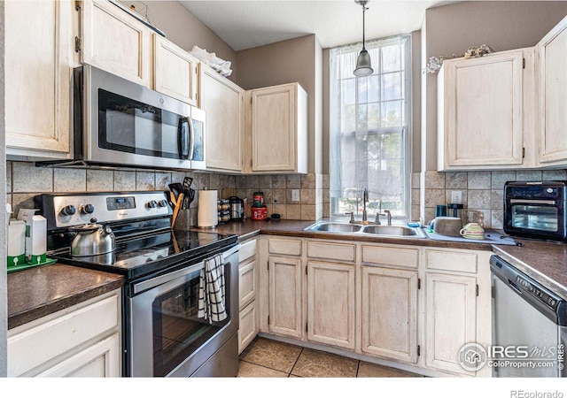 kitchen featuring light tile patterned floors, sink, decorative backsplash, hanging light fixtures, and appliances with stainless steel finishes