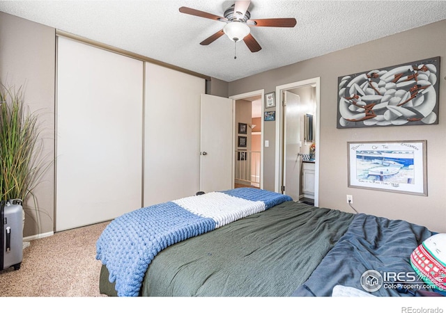 carpeted bedroom featuring a textured ceiling, connected bathroom, ceiling fan, and a closet