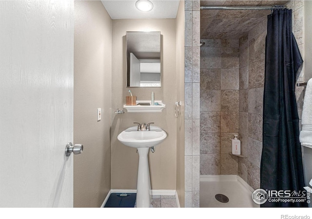 bathroom with curtained shower, sink, and tile patterned floors