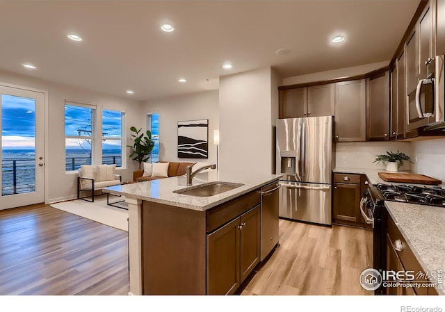 kitchen featuring light hardwood / wood-style flooring, stainless steel appliances, sink, and an island with sink