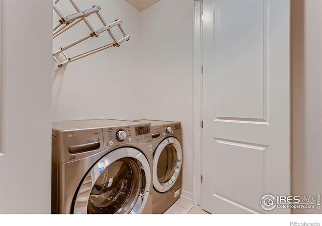 clothes washing area with light tile patterned floors and washer and dryer