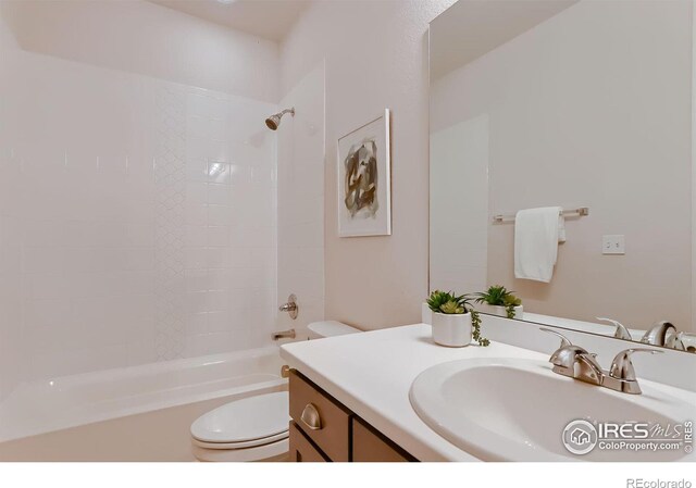 full bathroom featuring tiled shower / bath, vanity, and toilet