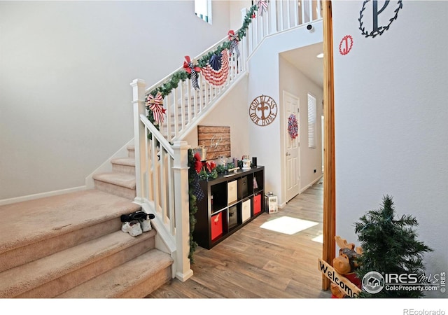 stairway with a high ceiling and hardwood / wood-style floors