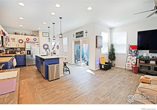 kitchen featuring appliances with stainless steel finishes, a breakfast bar area, light hardwood / wood-style floors, and a kitchen island with sink