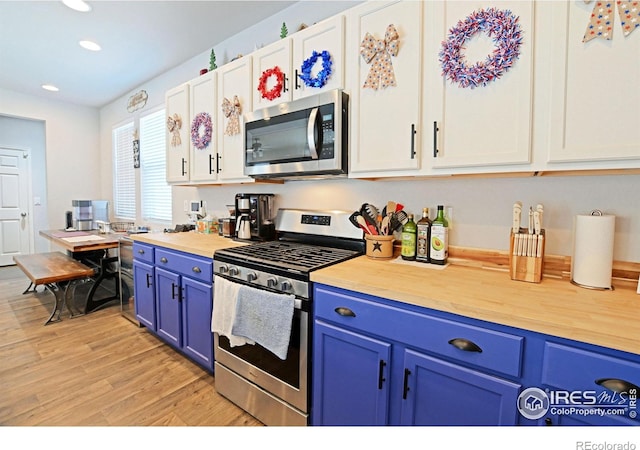 kitchen with blue cabinets, white cabinetry, light hardwood / wood-style flooring, and stainless steel appliances