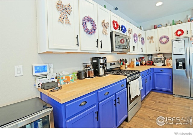 kitchen with blue cabinets, stainless steel appliances, light wood-type flooring, and white cabinets