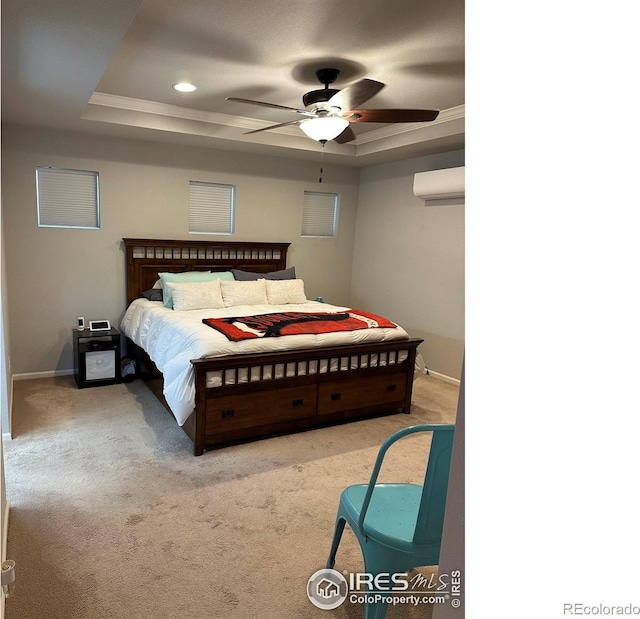 bedroom featuring a wall mounted air conditioner, ornamental molding, ceiling fan, carpet flooring, and a tray ceiling