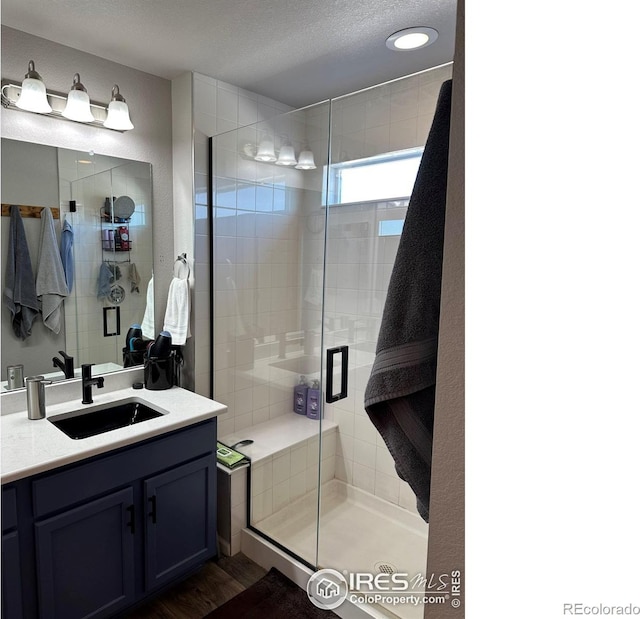 bathroom featuring an enclosed shower, hardwood / wood-style flooring, a textured ceiling, and vanity