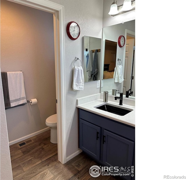 bathroom with vanity, toilet, and hardwood / wood-style flooring