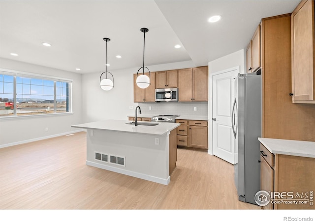 kitchen with light wood finished floors, stainless steel appliances, tasteful backsplash, visible vents, and a sink