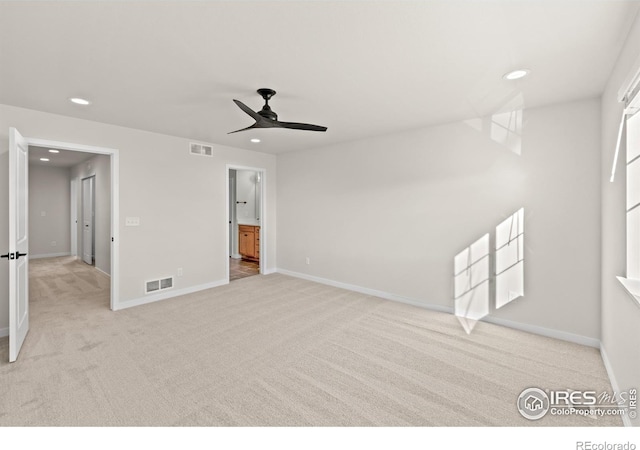 interior space featuring light colored carpet, ensuite bath, and ceiling fan