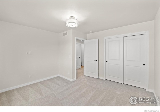 unfurnished bedroom with light colored carpet and a closet