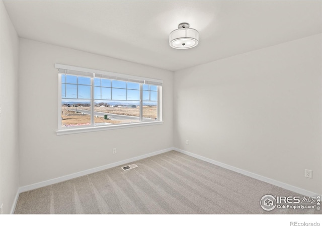 empty room featuring carpet flooring, visible vents, and baseboards