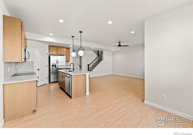 kitchen featuring ceiling fan, an island with sink, decorative light fixtures, appliances with stainless steel finishes, and light wood-type flooring