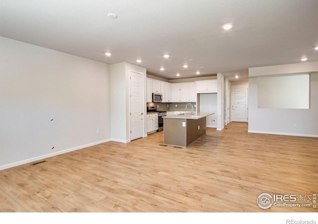 kitchen featuring a center island with sink, light hardwood / wood-style floors, stainless steel appliances, sink, and white cabinets