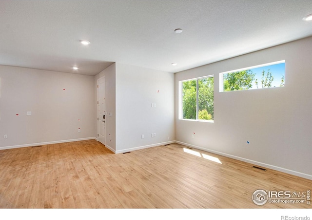 unfurnished room featuring light wood-type flooring and a textured ceiling