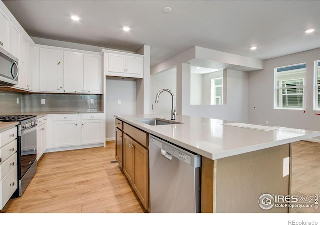 kitchen featuring white cabinets, appliances with stainless steel finishes, a center island with sink, and sink