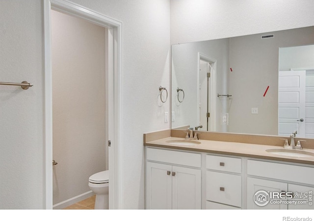 bathroom featuring tile patterned flooring, toilet, and vanity