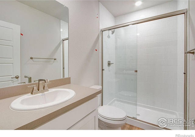 bathroom with vanity, toilet, wood-type flooring, and a shower with shower door