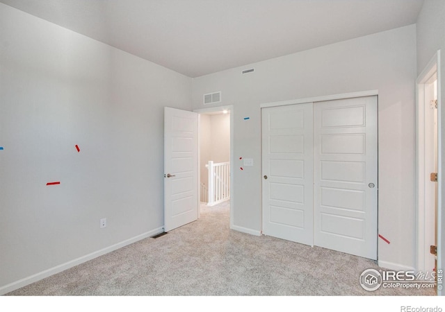 unfurnished bedroom featuring light carpet and a closet