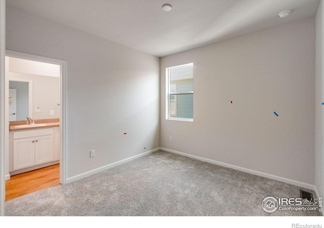 interior space featuring ensuite bath, sink, and light colored carpet