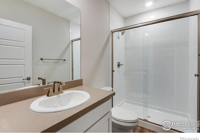 bathroom with a shower with door, vanity, and toilet