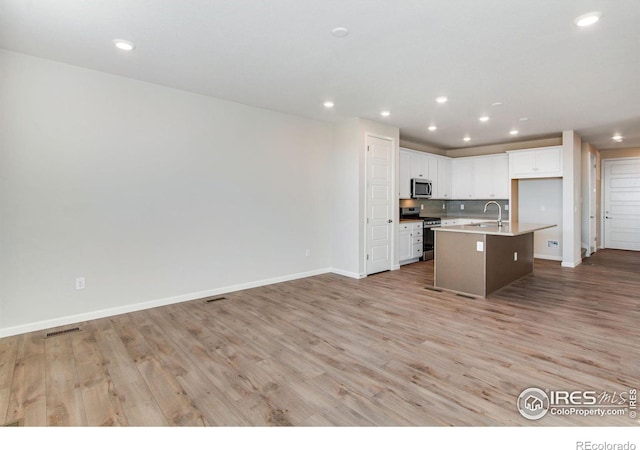 kitchen featuring an island with sink, appliances with stainless steel finishes, white cabinets, and light hardwood / wood-style flooring