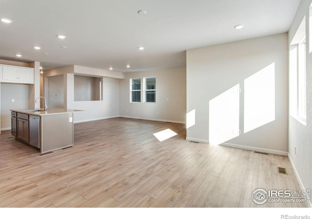 kitchen with dishwasher, sink, white cabinets, a kitchen island with sink, and light hardwood / wood-style flooring