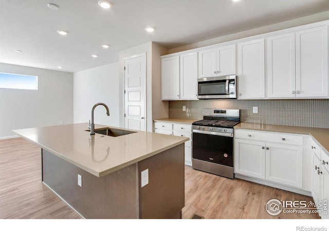 kitchen featuring sink, stainless steel appliances, white cabinets, and a center island with sink