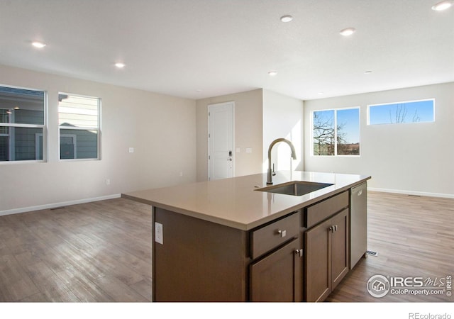 kitchen featuring dishwasher, sink, a center island with sink, and light hardwood / wood-style floors