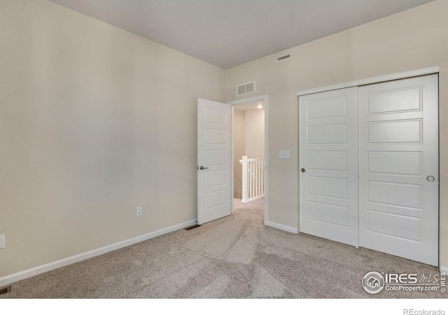 unfurnished bedroom featuring light colored carpet and a closet