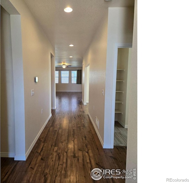 hall with a textured ceiling, built in features, and dark hardwood / wood-style flooring