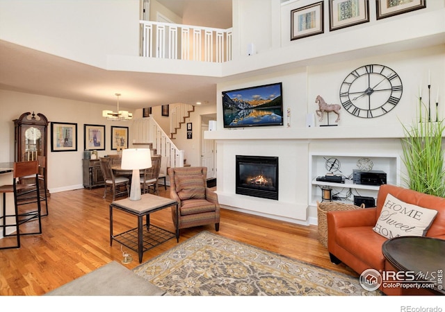 living room featuring light hardwood / wood-style flooring, a notable chandelier, and a towering ceiling