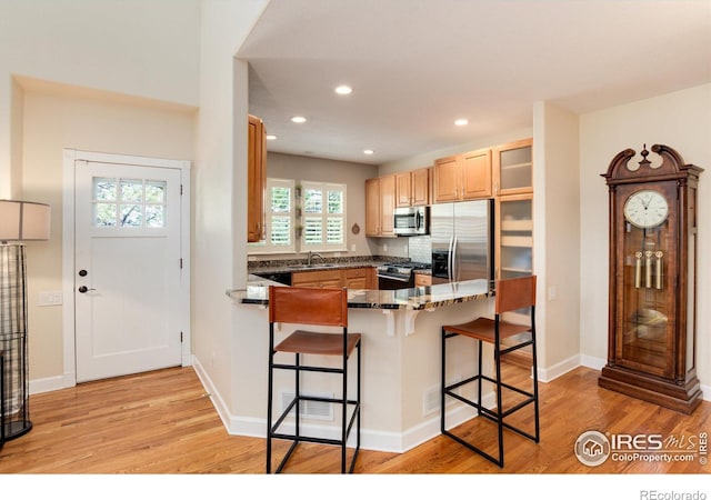 kitchen featuring a breakfast bar area, a wealth of natural light, stainless steel appliances, and light hardwood / wood-style floors