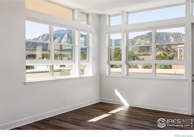 unfurnished room with dark wood-type flooring and a mountain view