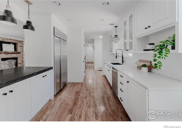 kitchen featuring pendant lighting, tasteful backsplash, light hardwood / wood-style flooring, stainless steel appliances, and sink