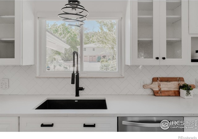 kitchen featuring white cabinetry, decorative light fixtures, an inviting chandelier, sink, and stainless steel dishwasher