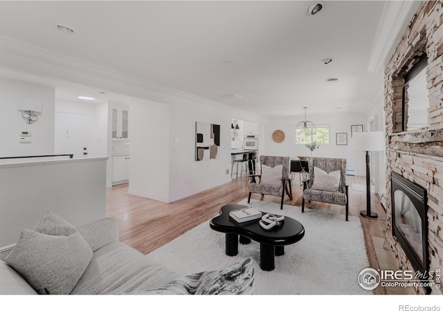 living room featuring light hardwood / wood-style flooring, ornamental molding, and a stone fireplace