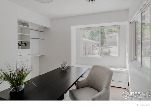 home office featuring light wood-type flooring, a baseboard radiator, and a wealth of natural light